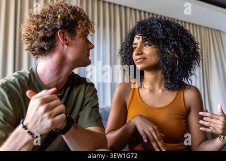 Diverse coppie sedute sul divano nel salotto, donne che gestiscono mentre un uomo indossa l'orologio da polso ascolta Foto Stock
