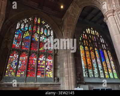 Vetrate colorate con motivi astratti incastonate in archi gotici in pietra all'interno di una cattedrale. Foto Stock