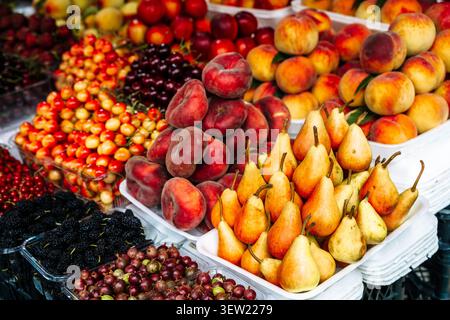 Vivace assortimento di frutta fresca di stagione. Prodotti estivi, tra cui ciliegie, lamponi, pesche, pere, e gelsi, che mostrano le loro texture naturali e le loro tonalità luminose e invitanti. Foto Stock