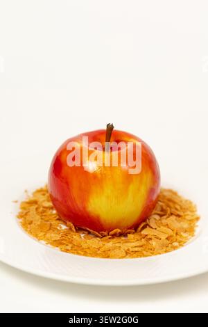 Una mousse 3D di alta qualità realizzata realisticamente come una mela rossa e gialla lucida con finitura a specchio, decorata con cialde su un bianco Foto Stock