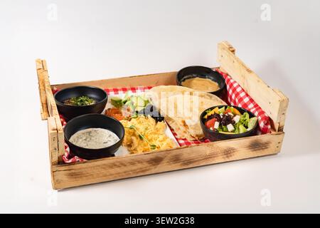 Colazione combinata con uova strapazzate, salmone e focaccia in una cassa di legno. Foto Stock