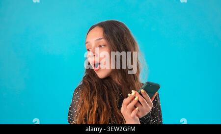 Donna sorpresa che guarda il suo schermo del telefono con gli occhi larghi e si sente molto scioccata Foto Stock