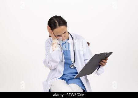 Medico donna in possesso di una cartella paziente e che guarda le cartelle cliniche nelle sue mani Foto Stock