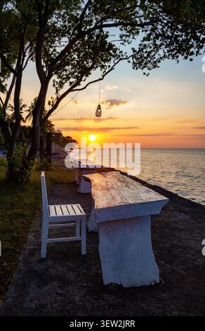 Tavolo e sedia in riva al mare, Bali, Indonesia, Sud-est asiatico. Tavolo e sedia per rilassarsi al tramonto, Bali, Indonesia. Foto Stock