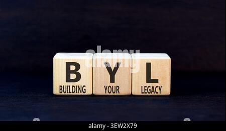 BYL sta costruendo il tuo simbolo legacy. Parole concettuali BYL costruisce la tua eredità su splendidi blocchi di legno. Splendido sfondo nero. Business BYL Building Foto Stock