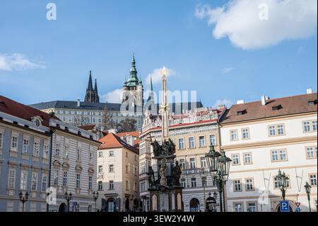 Vista a livello della strada della Colonna della Santa Trinità in Malostranské náměstí circondata da facciate storiche, con le guglie della Cattedrale di San Vito che si ergono in Foto Stock