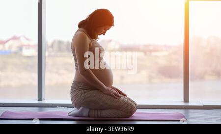 Donna incinta che pratica yoga per il benessere prenatale Foto Stock