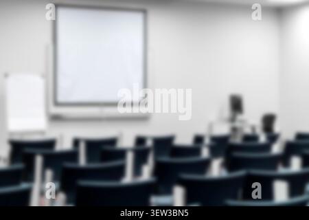 Aula universitaria o classe vuota e sfocata con sedie blu, schermo proiettore, flipchart. Presentazione accademica, sfondo per seminario educativo. Foto Stock
