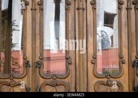 Le porte in legno splendidamente lavorate mostrano riflessi di vivaci attività nelle vicinanze. Foto Stock