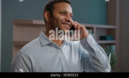 Allegro uomo d'affari indiano arabo parlare telefono cellulare chiamare ufficio discutere di lavoro imprenditore di successo uomo d'affari smartphone di lingua maschile Foto Stock