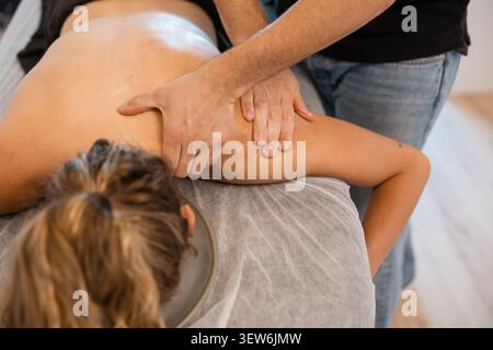 Fisioterapista che esegue la terapia manuale sulla spalla della donna Foto Stock