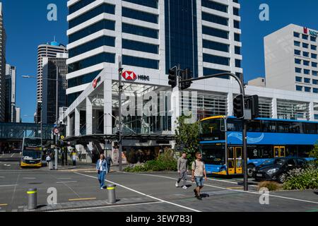 Pedoni attraversano una strada vicino all'edificio HSBC, illustrando le operazioni bancarie internazionali e le tendenze di ristrutturazione aziendale nella città. Foto Stock
