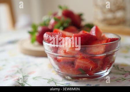 Ciotola di fragole appena tagliate su un tavolo Foto Stock