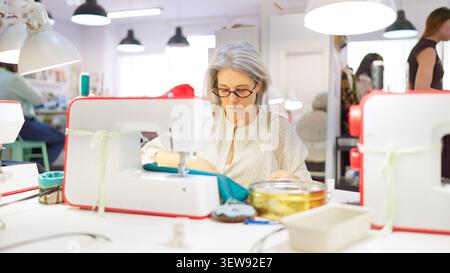 Donna anziana che impara a cucire il mestiere in laboratorio creativo Foto Stock