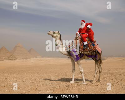 Babbo Natale in costume rosso cavalca un cammello decorato in modo luminoso prima delle iconiche piramidi di Giza nel deserto egiziano, un giocoso viaggio natalizio Foto Stock