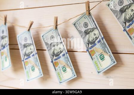 Banconote in dollari USA appese su una clothesline con clothespins su sfondo di legno Foto Stock