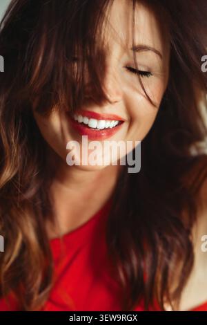 Donna gioiosa con un bel sorriso e capelli disordinati Foto Stock