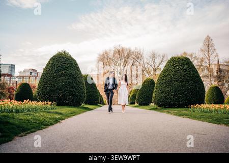 Coppia felice che cammina mano nella mano attraverso un parco Foto Stock