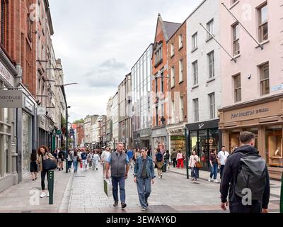 Persone che camminano lungo Grafton Street, una famosa strada commerciale per lo shopping a Dublino, Irlanda, caratterizzata da negozi e architettura urbana. Foto Stock