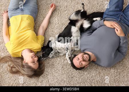 Una coppia felice e il loro cane sdraiati sul pavimento, vista dall'alto Foto Stock