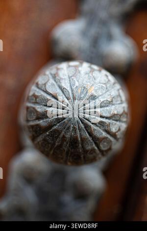 Primo piano estremo di una maniglia per porta in metallo antico incisa che mette in risalto la maestria decorativa e la superficie ruvida. Foto Stock