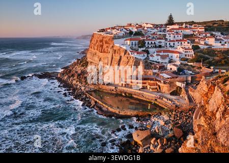 Vista mozzafiato di Azenhas do Mar, un affascinante villaggio sul mare arroccato sulle scogliere dell'oceano Atlantico. I colori caldi del tramonto evidenziano il pictu Foto Stock