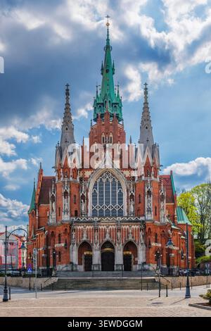 Vista ravvicinata della chiesa di San Giuseppe a Podgorze, Cracovia, Polonia, che mostra l'architettura gotica in mattoni rossi, alti campanili, facciata della chiesa, cielo blu e non p Foto Stock