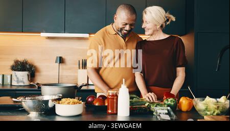 Cucinare, sorridere o coppia in cucina con aiuto, attività di incollaggio o connessione nella preparazione dei pasti. Amore, cura o persone mature in casa con il cibo, felici Foto Stock