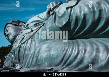 Enorme statua di Buddha sdraiato al tempio Nanzoin a Sasaguri, prefettura di Fukuoka, Giappone, fotografata da un drammatico angolo basso contro un cielo azzurro. Foto Stock