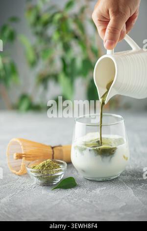Il tè Matcha viene versato in latte freddo. Sana bevanda vegana Matcha latte Foto Stock