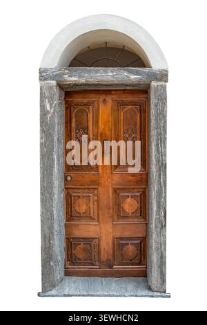 Storica porta doppia in legno decorata con eleganti pannelli floreali scolpiti a mano e tradizionale battente in ferro, incorniciata da un rustico arco alpino in pietra e. Foto Stock