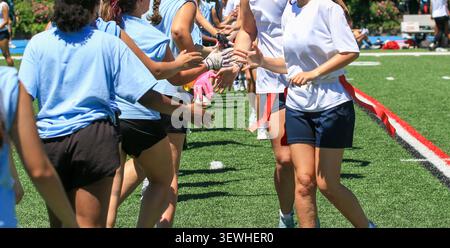 I giocatori con maglie blu si stringono la mano dopo una partita di flag football sul campo. Foto Stock