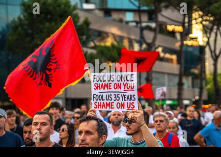 Tirana, Albania - 25 giugno 2026: I manifestanti sventolano bandiere albanesi e tengono slogan politici durante una manifestazione antigovernativa. Foto Stock
