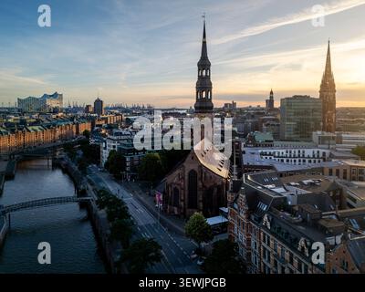 Vista aerea della storica guglia della chiesa di Santa Caterina che si erge sopra l'architettura in mattoni del quartiere di Speicherstadt con l'Elbphilharmonie in Foto Stock