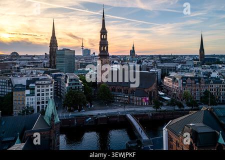 Vista aerea della chiesa di Santa Caterina circondata da architettura urbana storica, tetti e canale al tramonto ad Amburgo, Amburgo, Germania. Foto Stock