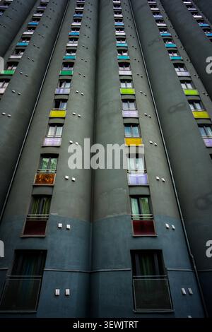 Una vista dall'alto, dall'angolazione bassa, rivela un alto edificio residenziale con più pinne verticali di cemento che separano file di finestre, ciascuna con un bricco Foto Stock