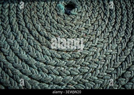 Una corda verde spessa e resistente agli agenti atmosferici è strettamente intrecciata in cerchi concentrici, formando un intricato motivo intrecciato lungo il telaio. La corda sembra ben u Foto Stock