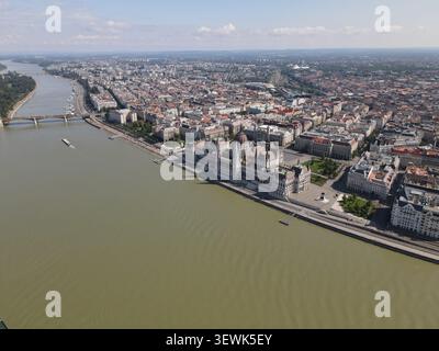 L'edificio del Parlamento ungherese si trova sulla riva del Danubio a Budapest, in Ungheria, circondato da edifici cittadini e da un ponte che attraversa il Foto Stock