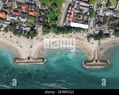 Vista aerea della spiaggia di Sanur con acque turchesi, costa sabbiosa, frangiflutti in pietra e edifici circostanti a Denpasar, Bali, Indonesia. Foto Stock