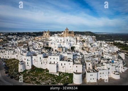 Una vista aerea cattura gli storici edifici bianchi di Ostuni, in Italia, raggruppati su una collina. L'importante cattedrale della città con il suo distintivo Foto Stock