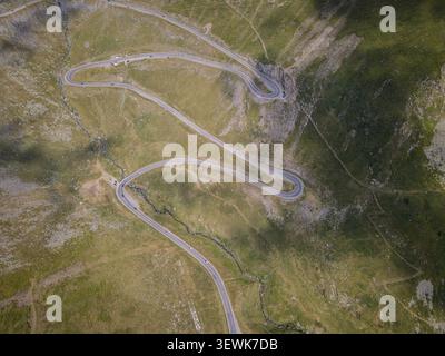 Lo scatto aereo cattura la tortuosa strada di montagna Transfagarasan mentre serpeggia attraverso verdi pendii e terreni rocciosi. Questa strada iconica è conosciuta per me Foto Stock