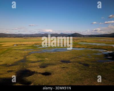 Una vista aerea grandangolare cattura il campo carsico del lago Cerknica, un vasto paesaggio paludoso caratterizzato da corpi idrici e vegetazione diversificata, sotto a. Foto Stock