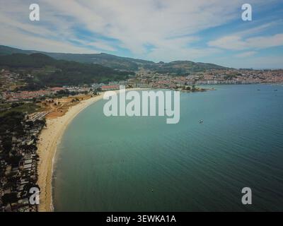 Uno scatto aereo cattura la spiaggia di Playa Major che si snoda verso la città di Portonovo, con l'Oceano Atlantico blu a destra e le verdi colline sul retro Foto Stock