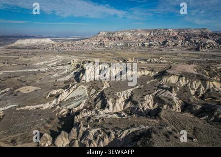 Questa ampia vista aerea cattura l'ampio e aspro terreno della Pigeon Valley in Cappadocia, Turchia, caratterizzato da formazioni di tufo erose e un lontano Foto Stock