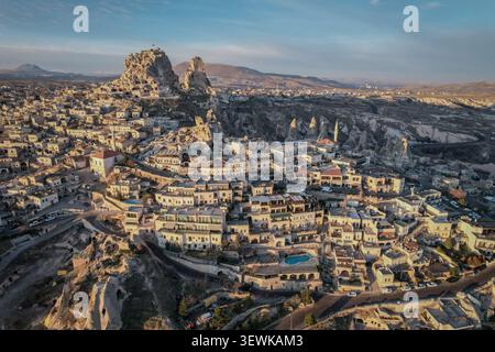 Una vista aerea grandangolare cattura il castello di Uchisar e la città di Uchisar in Cappadocia, Turchia, sotto la luce del mattino. Le storiche abitazioni nelle grotte e. Foto Stock