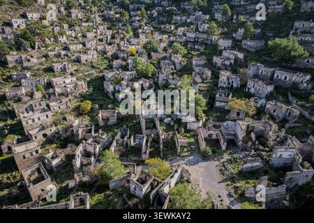 Una vista aerea grandangolare cattura centinaia di case in pietra abbandonate che coprono una collina nel villaggio fantasma di Kayaköy, vicino a Fethiye, in Turchia. Questo histori Foto Stock