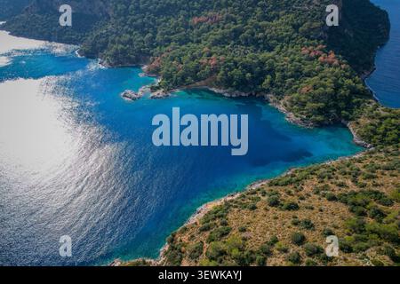Una vista aerea mostra la Valle delle Farfalle (Kelebekler Vadisi) a Oludeniz, Fethiye, Turchia, con acque turchesi che contrastano le scogliere boschive. Questo locati Foto Stock