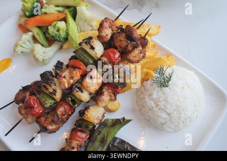 Spiedini di pollo alla griglia serviti con riso e verdure Foto Stock