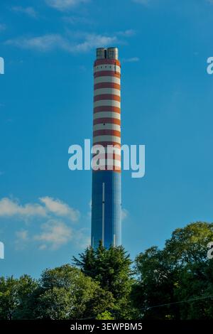 Panorama industriale e infrastrutturale catturato in una giornata limpida. Sul lato sinistro spiccano due grandi piloni ad alta tensione, caratterizzati da alternati Foto Stock