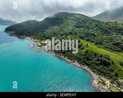 Vista aerea del turchese Lac du Mont-Cenis circondato da verdi colline, foreste e le vette del Mont-Cenis in Val-Cenis, Alvernia-Rodano-Alpes, fra Foto Stock